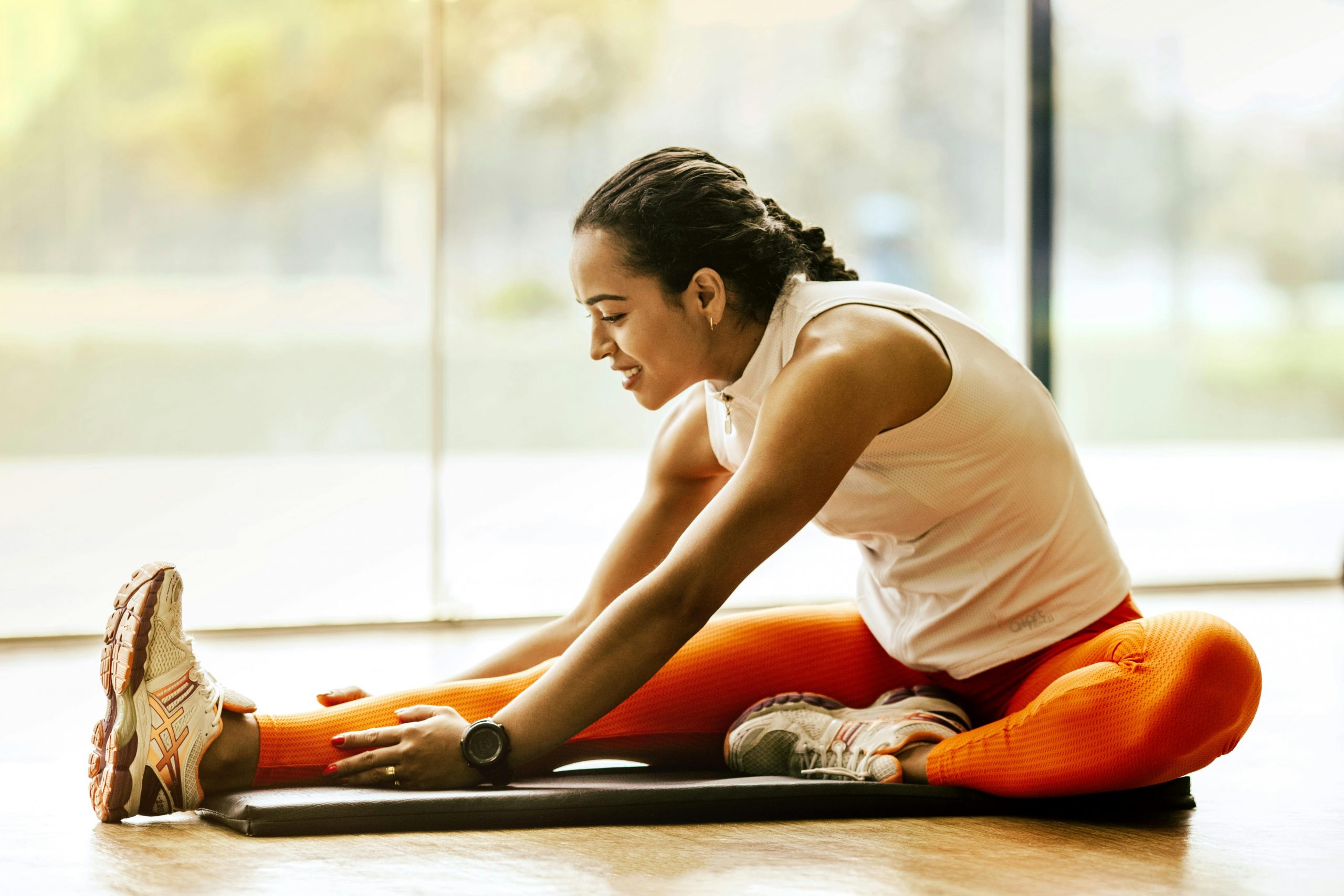 woman in orange yoga pants stretching wellness