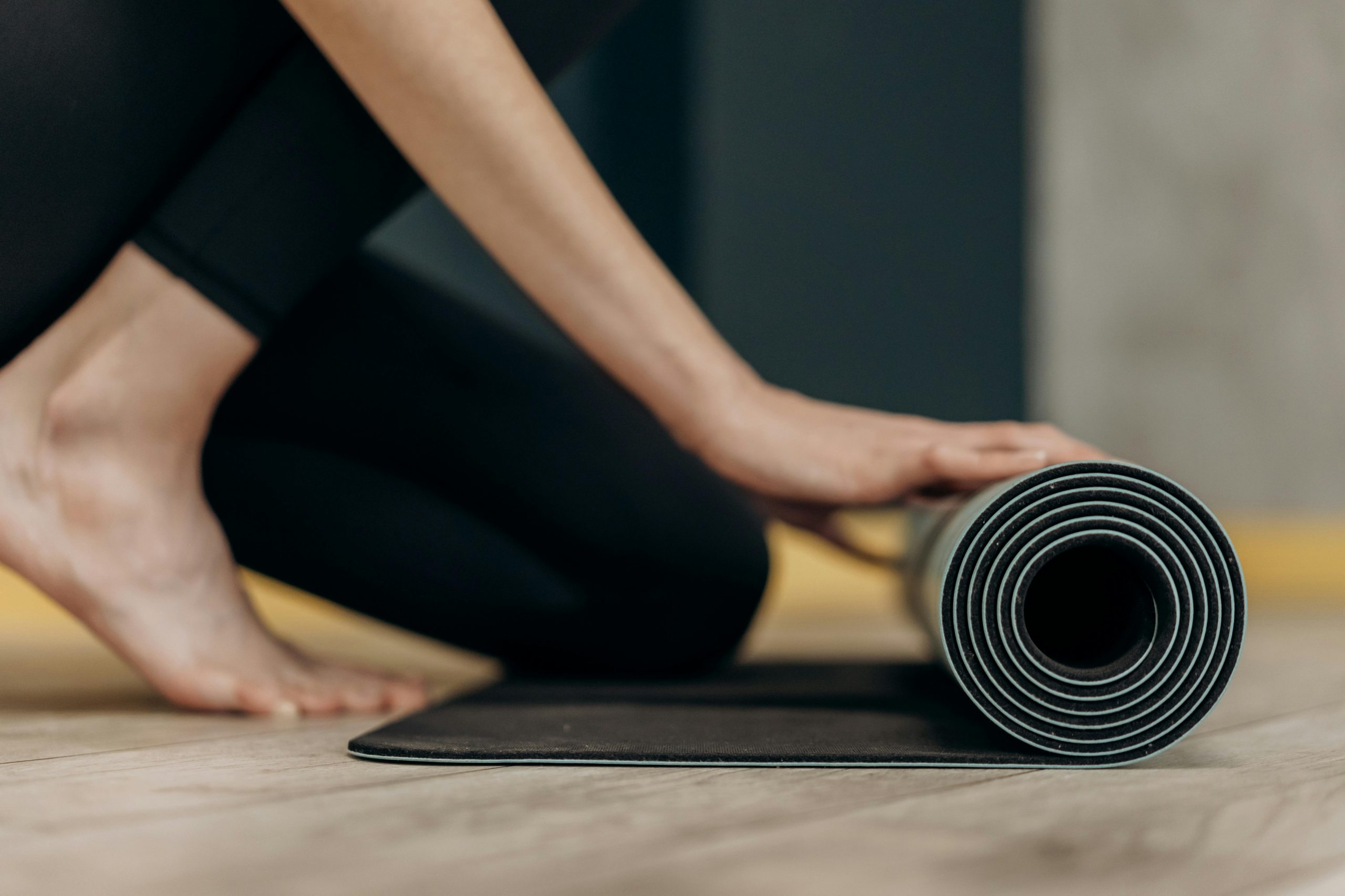 woman rolling up a black yoga mat