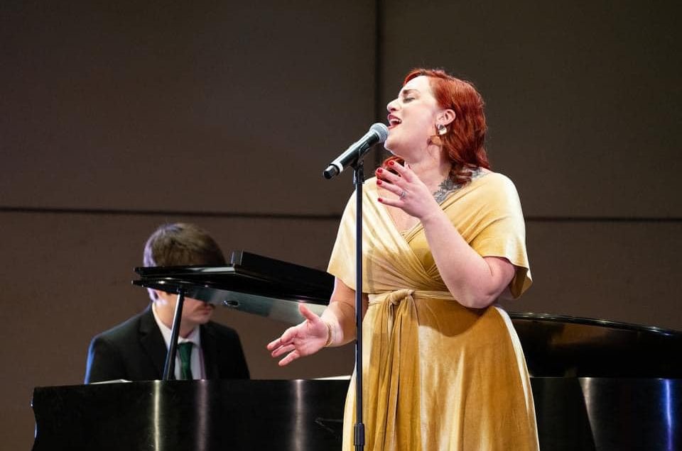 Kelly Knowlton singing into a microphone