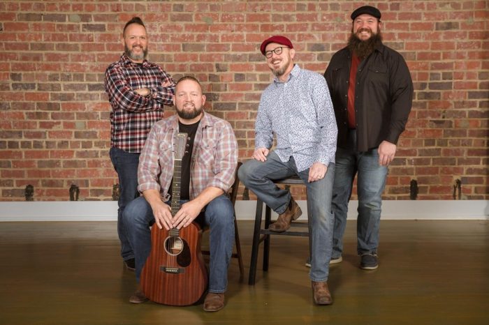 The Four members of Tom's Kitchen Table posing in front of a brick wall