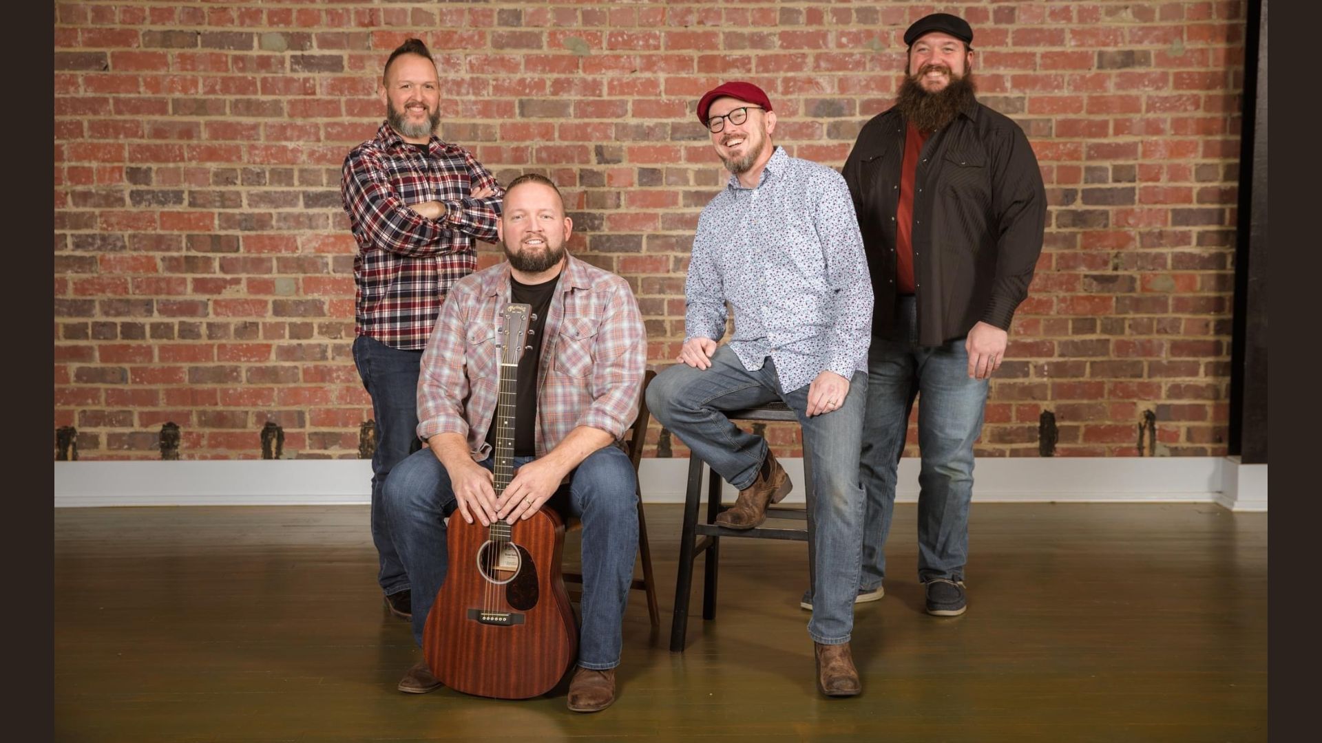 The Four members of Tom's Kitchen Table posing in front of a brick wall