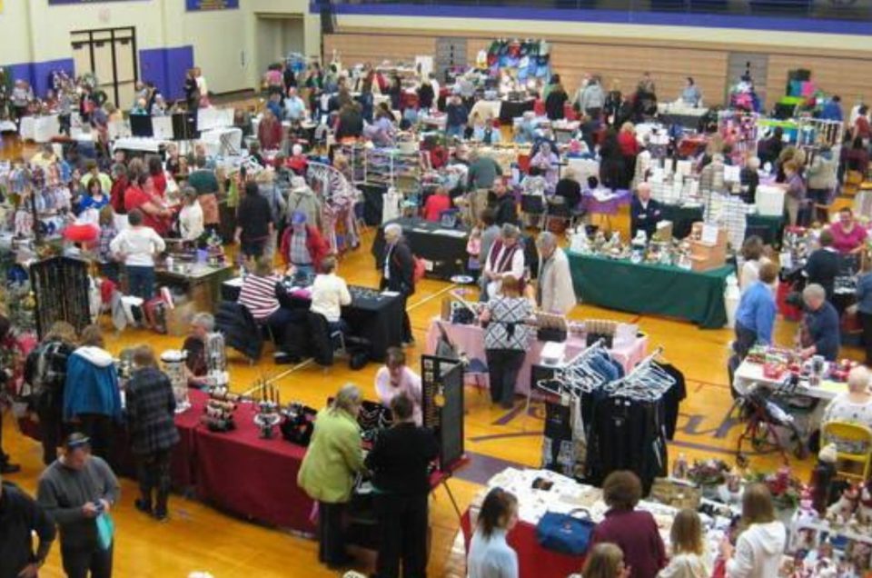 crowds of people shopping at a craft show in a gymnasium