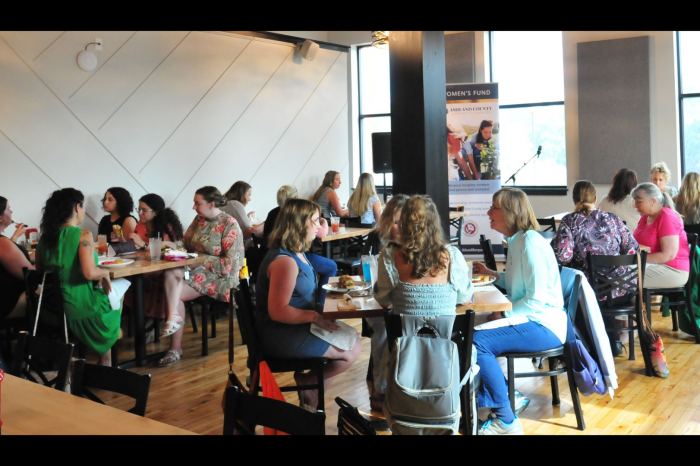 Women sitting in small groups at a restaurant chatting with each other while sharing a meal