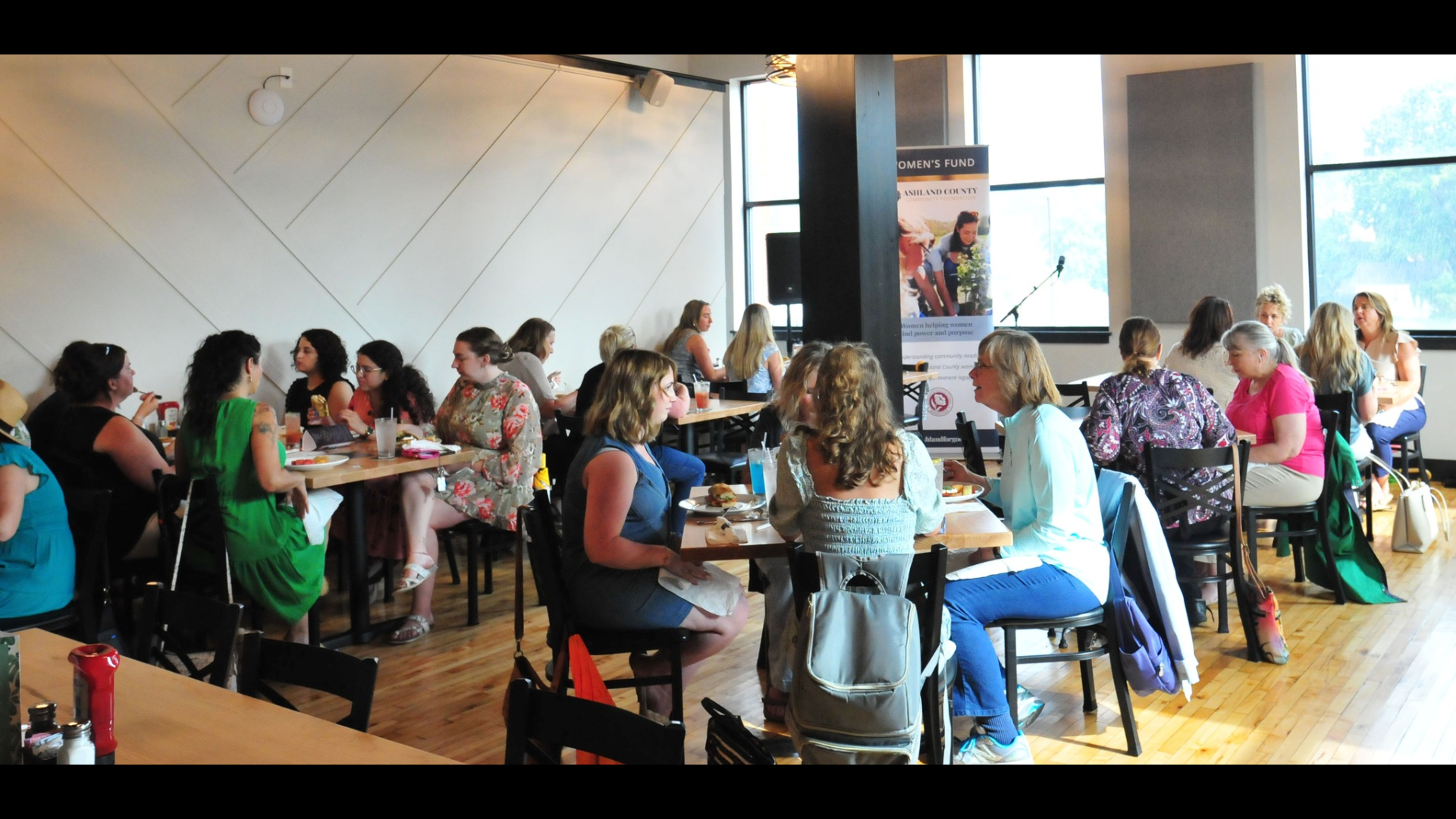 Women sitting in small groups at a restaurant chatting with each other while sharing a meal