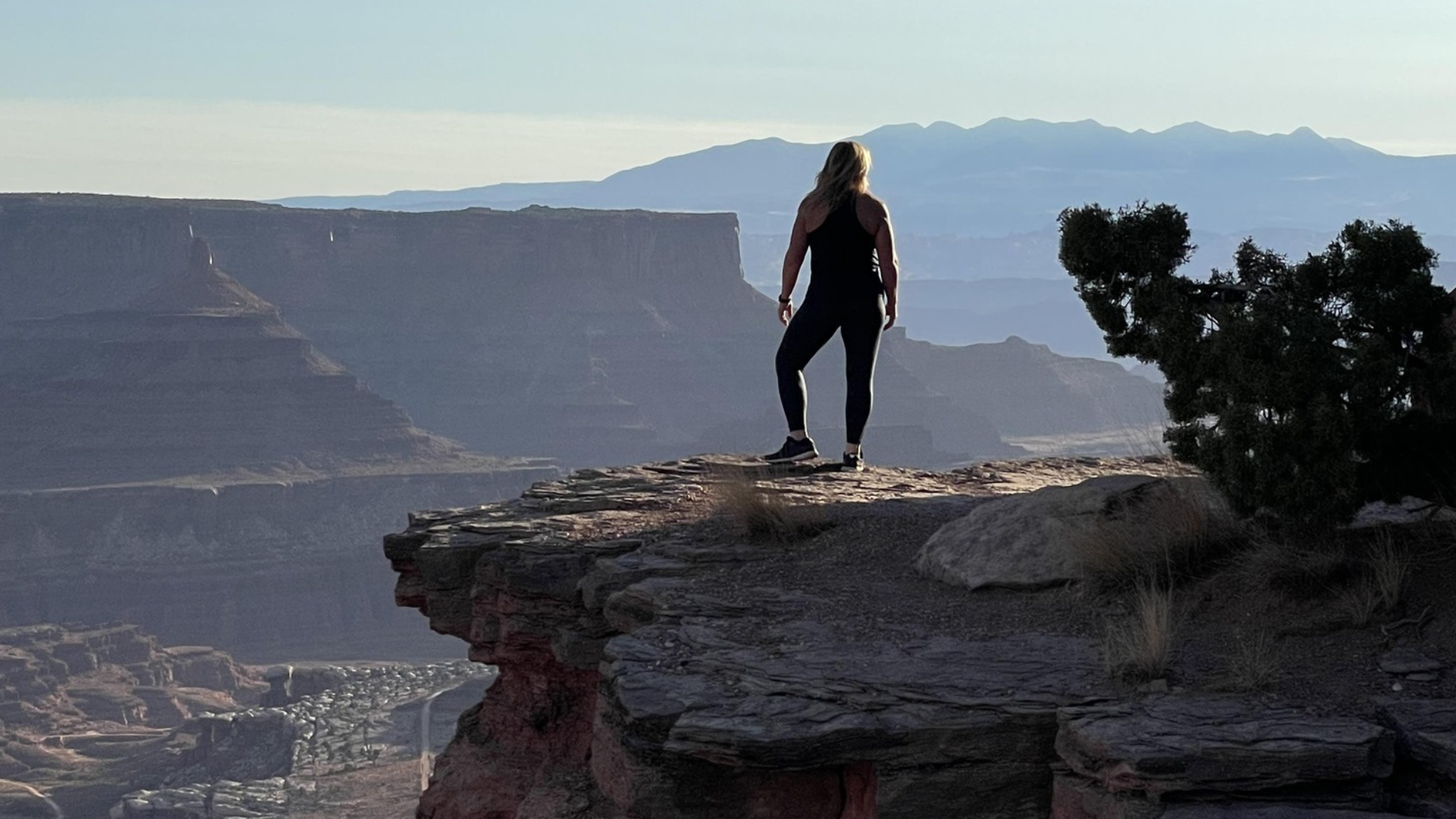 A woman in Athletic wear in the summer standing near what looks like the grand canyon