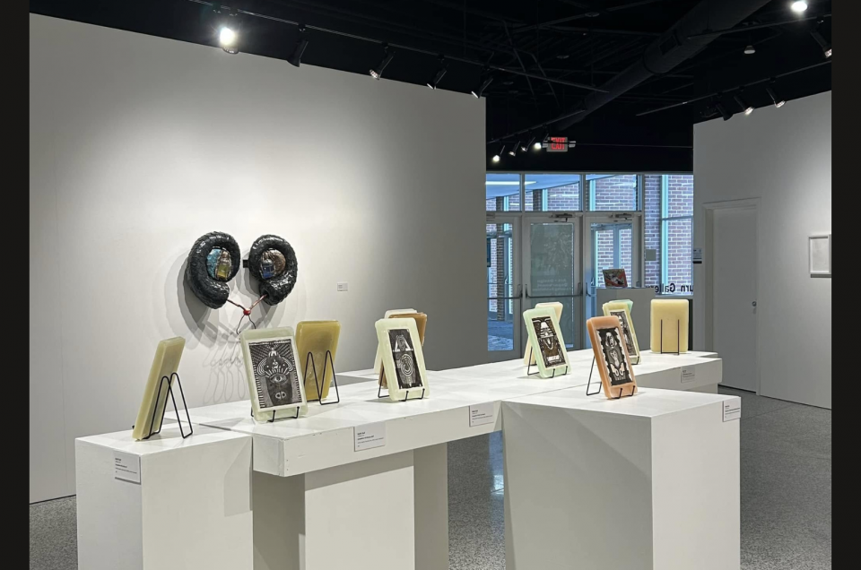 small pieces of art in frames and displayed on easels on white pedestals