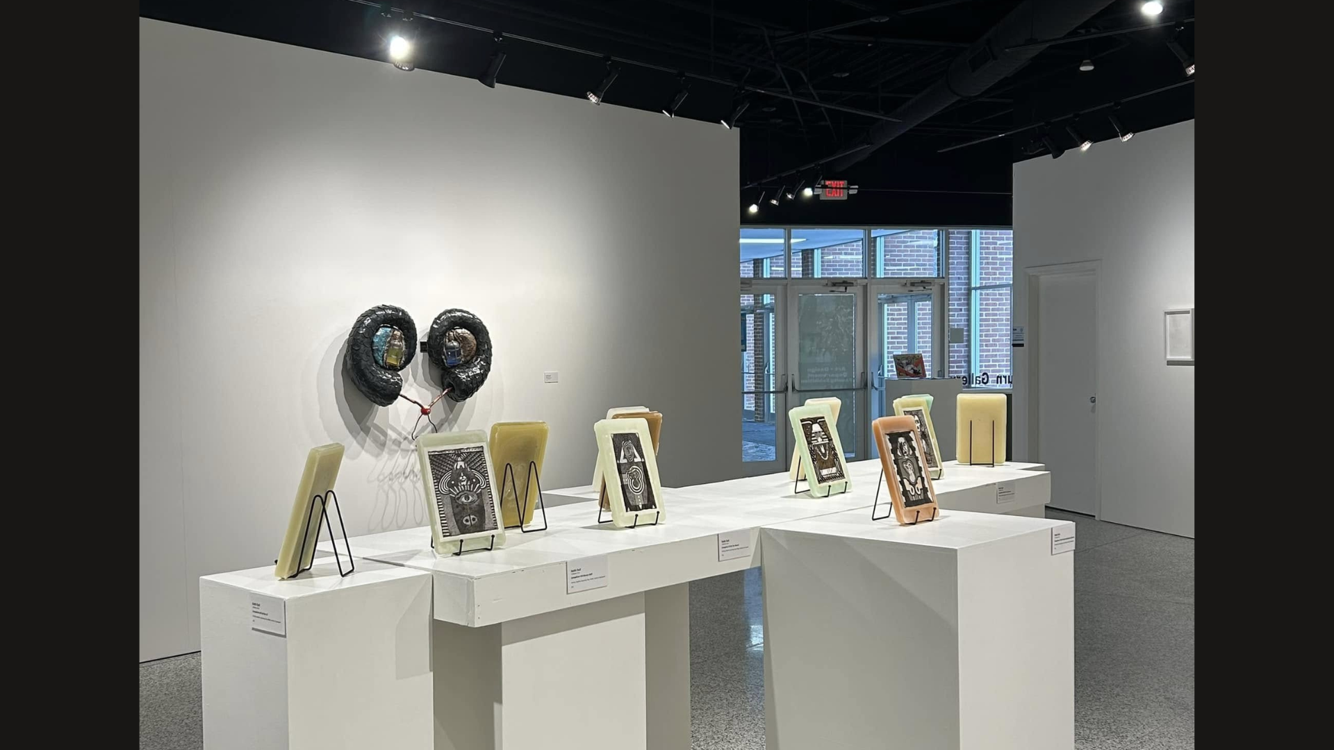 small pieces of art in frames and displayed on easels on white pedestals